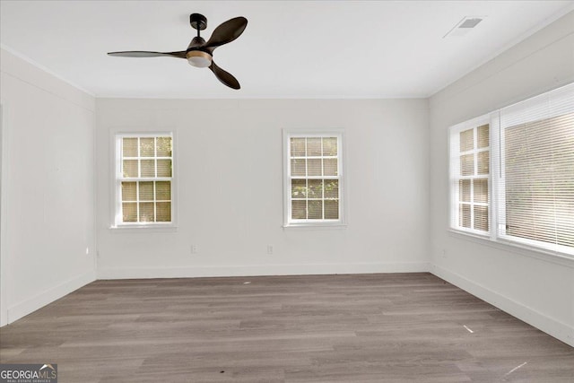 empty room featuring ceiling fan, wood finished floors, and a healthy amount of sunlight