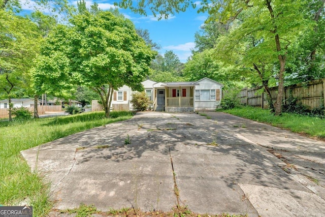 view of front of house featuring fence, driveway, and a porch
