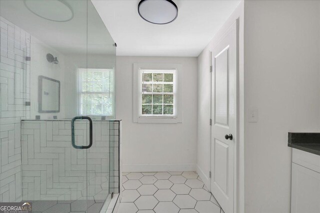 full bath featuring a stall shower, tile patterned flooring, vanity, and baseboards