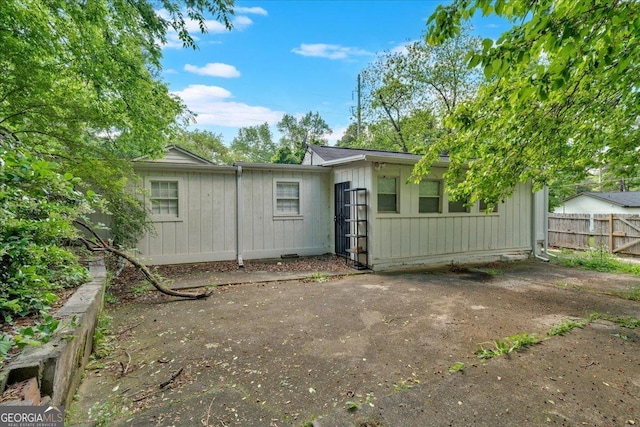 back of house featuring board and batten siding and fence