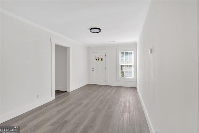 interior space featuring wood finished floors, crown molding, and baseboards