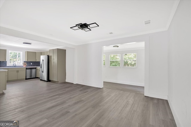 unfurnished living room with visible vents, crown molding, light wood-style flooring, and baseboards
