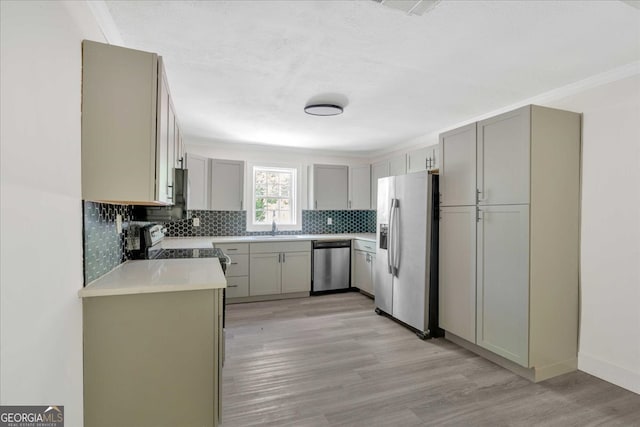 kitchen featuring a sink, decorative backsplash, light wood-style floors, gray cabinets, and appliances with stainless steel finishes