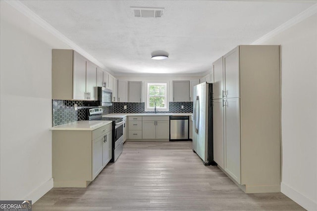 kitchen with a sink, tasteful backsplash, visible vents, light countertops, and appliances with stainless steel finishes