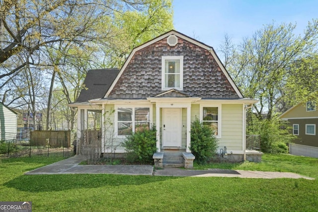 colonial inspired home with a front lawn, fence, and a gambrel roof