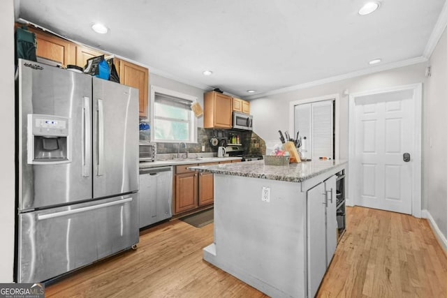 kitchen with light wood-style flooring, a center island, crown molding, and appliances with stainless steel finishes