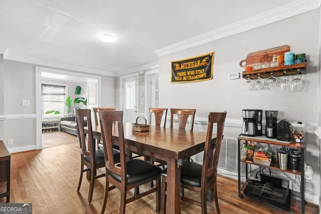 dining space with wood finished floors, ornamental molding, and plenty of natural light