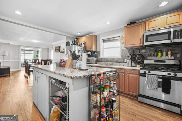 kitchen with tasteful backsplash, a sink, ornamental molding, stainless steel appliances, and a kitchen island