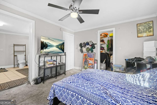 carpeted bedroom with a closet, baseboards, a spacious closet, crown molding, and ensuite bath