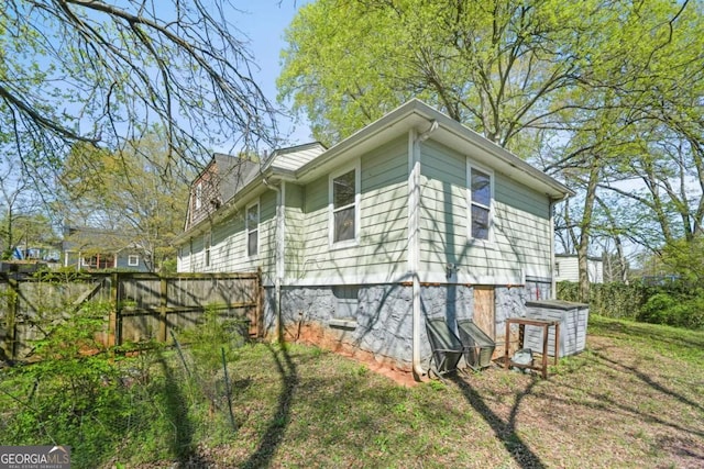 view of side of home with a yard and fence