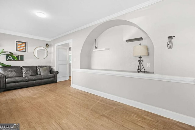 living area featuring arched walkways, baseboards, crown molding, and wood finished floors