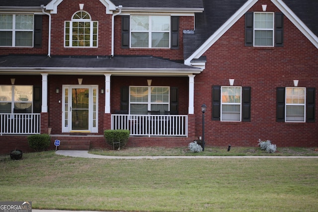 view of front facade featuring brick siding, a porch, and a front lawn