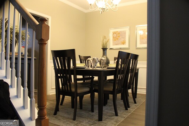 dining space with stairway, a notable chandelier, ornamental molding, wainscoting, and wood finished floors