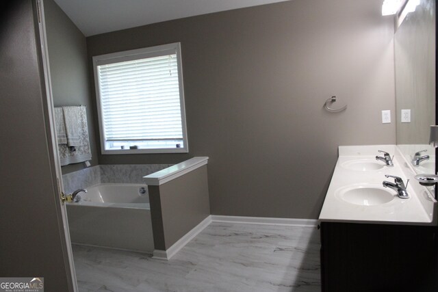 bathroom featuring marble finish floor, a bath, and a sink