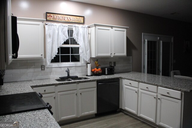 kitchen with a sink, tasteful backsplash, black appliances, a peninsula, and white cabinets