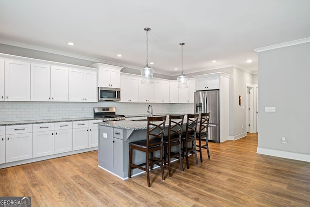 kitchen featuring stainless steel appliances, white cabinets, a kitchen breakfast bar, and a sink