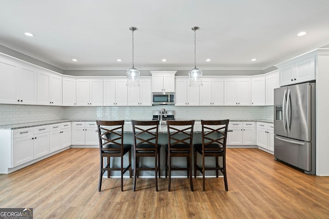 kitchen with stainless steel appliances, light wood-style floors, white cabinetry, and a kitchen bar