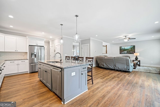 kitchen with a breakfast bar, recessed lighting, a ceiling fan, stainless steel appliances, and a sink