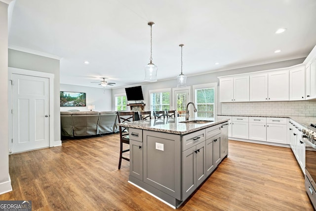 kitchen featuring a sink, ornamental molding, a ceiling fan, a kitchen bar, and gray cabinets