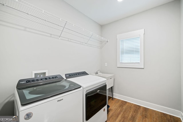 clothes washing area with baseboards, wood finished floors, washer and dryer, and laundry area