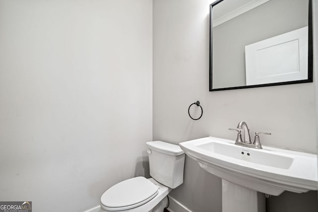 half bathroom with a sink, baseboards, and toilet