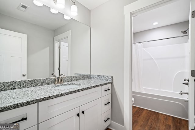 full bathroom with shower / tub combo, vanity, toilet, visible vents, and wood finished floors