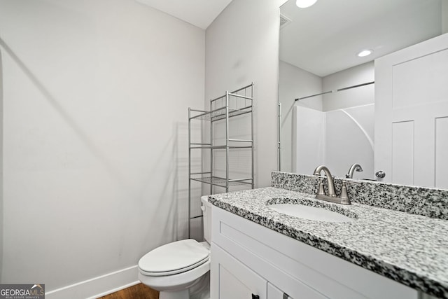bathroom with vanity, visible vents, toilet, wood finished floors, and baseboards