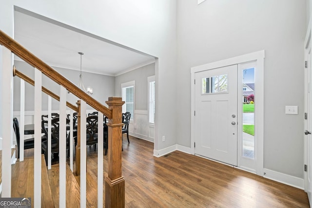 entrance foyer featuring a chandelier, plenty of natural light, ornamental molding, and wood finished floors