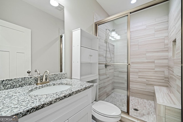 bathroom with visible vents, toilet, a stall shower, and vanity