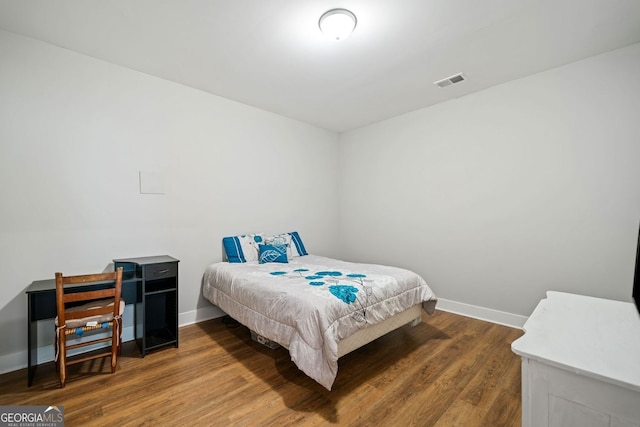 bedroom featuring wood finished floors, baseboards, and visible vents