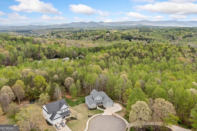 aerial view featuring a wooded view and a mountain view