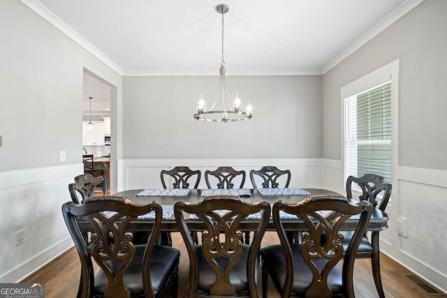 dining room featuring an inviting chandelier, wainscoting, ornamental molding, and dark wood finished floors