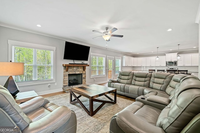 living room with baseboards, a ceiling fan, a fireplace, recessed lighting, and light wood finished floors