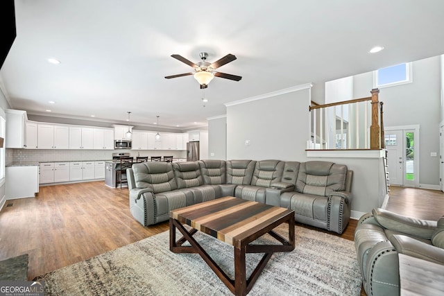 living room with ornamental molding, ceiling fan, recessed lighting, and light wood finished floors