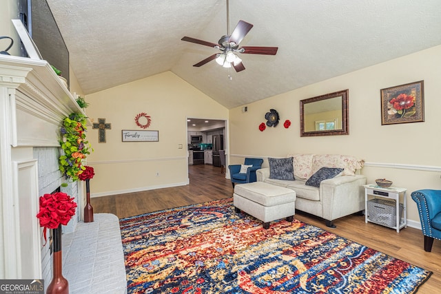 310 Hamdon Kells, Peachtree City, GA 30269 - living room with a textured ceiling, a ceiling fan, baseboards, wood finished floors, and vaulted ceiling