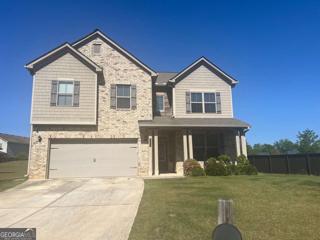 craftsman inspired home with a front lawn, driveway, fence, brick siding, and a garage