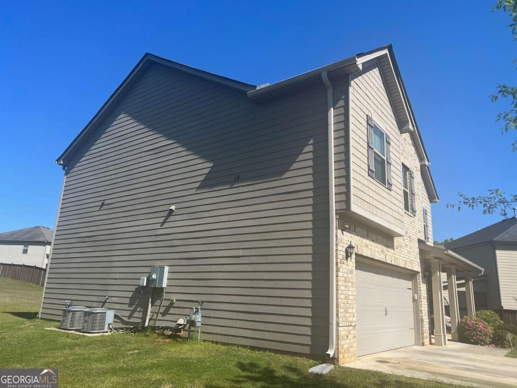 view of side of home with a lawn, driveway, central air condition unit, and a garage