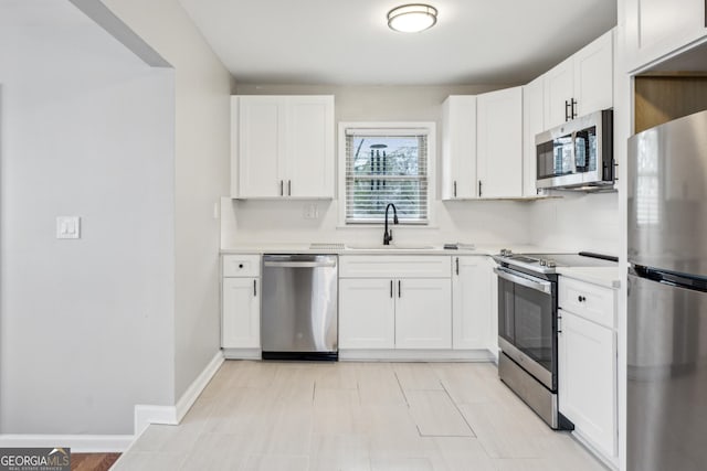 kitchen with a sink, light countertops, appliances with stainless steel finishes, and white cabinets