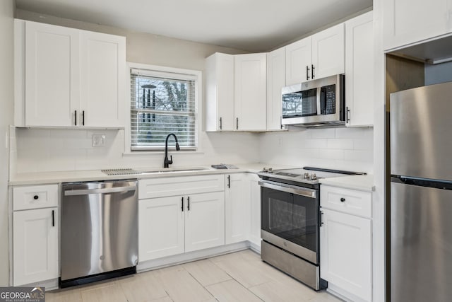 kitchen featuring tasteful backsplash, light countertops, white cabinetry, appliances with stainless steel finishes, and a sink