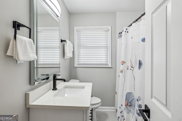 bathroom with toilet, a shower with shower curtain, vanity, and baseboards
