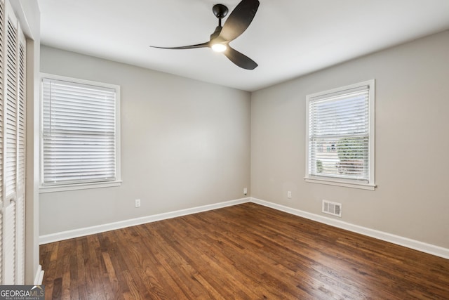 empty room featuring wood finished floors, baseboards, a ceiling fan, and visible vents