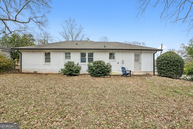 rear view of property featuring brick siding, a shingled roof, and crawl space