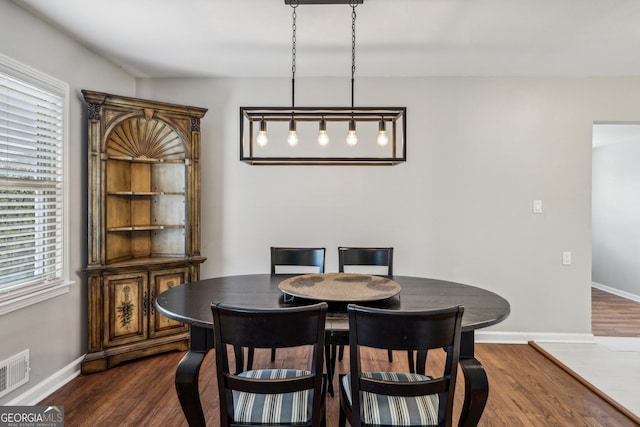 dining area with visible vents, dark wood-style flooring, and baseboards