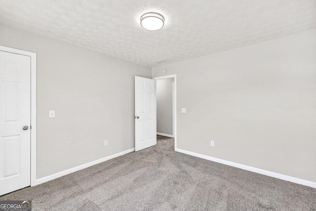empty room with a textured ceiling, carpet flooring, and baseboards