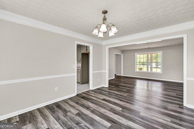 spare room with a textured ceiling, wood finished floors, a notable chandelier, and baseboards