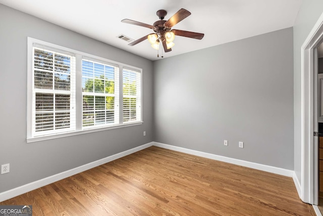 spare room with light wood finished floors, visible vents, baseboards, and a ceiling fan