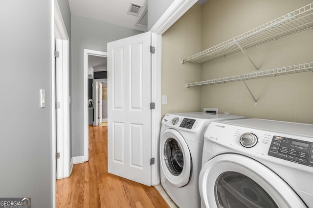 laundry area featuring light wood-type flooring, separate washer and dryer, laundry area, and visible vents