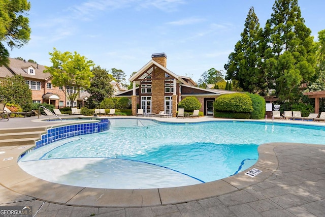community pool with a patio area and a community hot tub