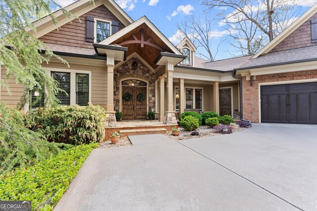 176 Stamp Mill Ln, Dahlonega, GA 30533 - property entrance featuring roof with shingles, concrete driveway, a garage, and stone siding
