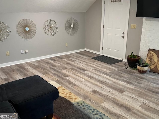living room featuring baseboards, wood finished floors, and lofted ceiling